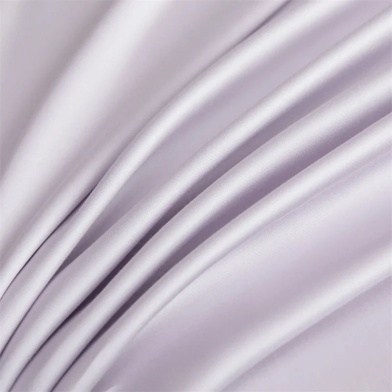 A close-up of a silky soft, light purple bamboo flat sheet draped in flowing folds.