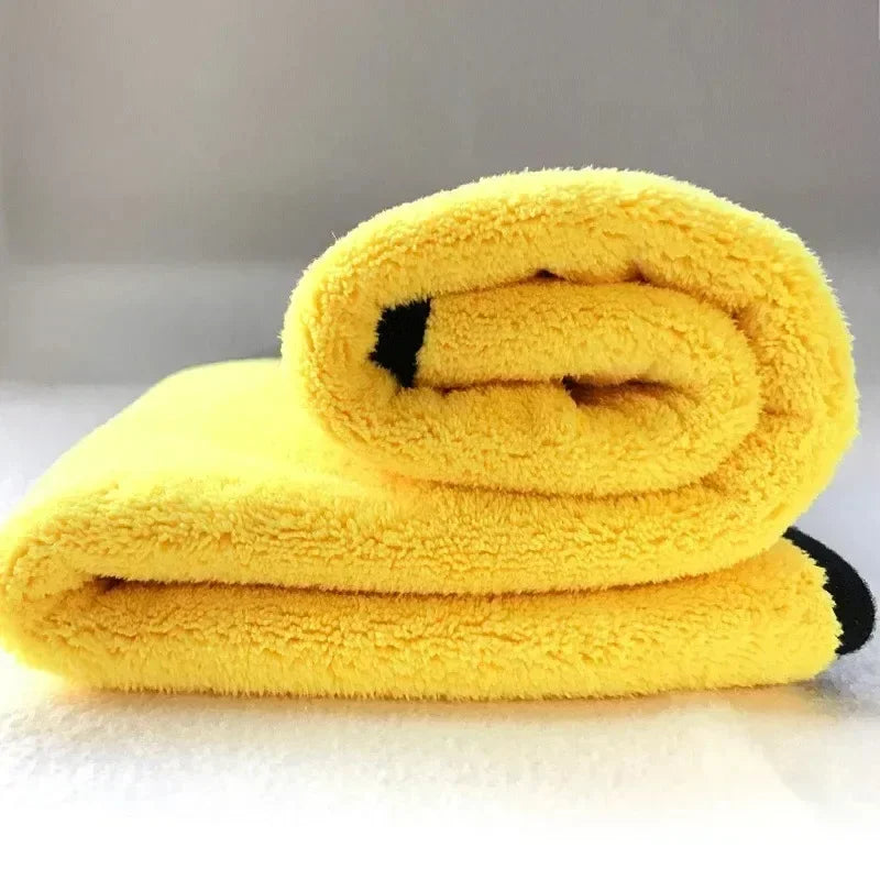A stack of bright yellow microfiber cleaning towels rolled up on a white surface.
