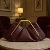 A deep burgundy soft PU leather crossbody bag with gold hardware resting on a marble surface.