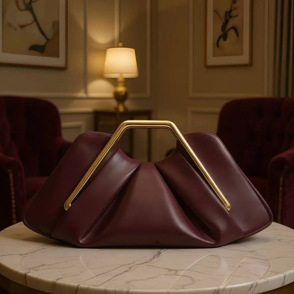 A deep burgundy soft PU leather crossbody bag with gold hardware resting on a marble surface.