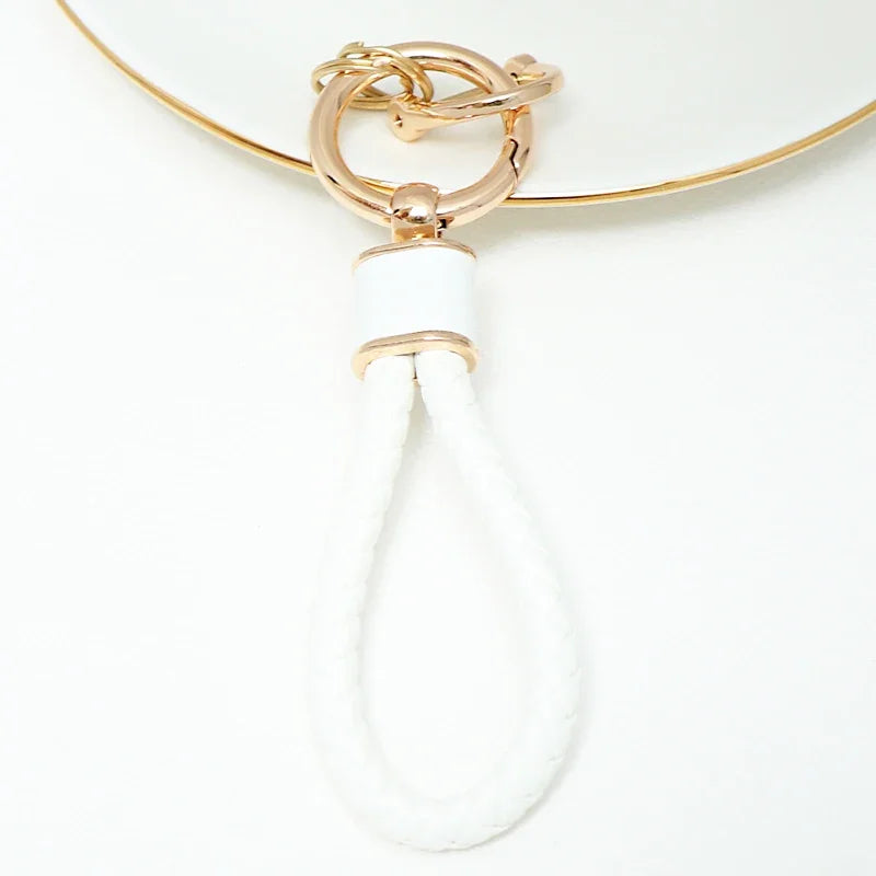 Gold-toned key fob cover with a white cord and loop for a Nissan car key.