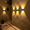 A wall featuring a pattern of upward-pointing LED lights illuminating a textured wall and a pathway.