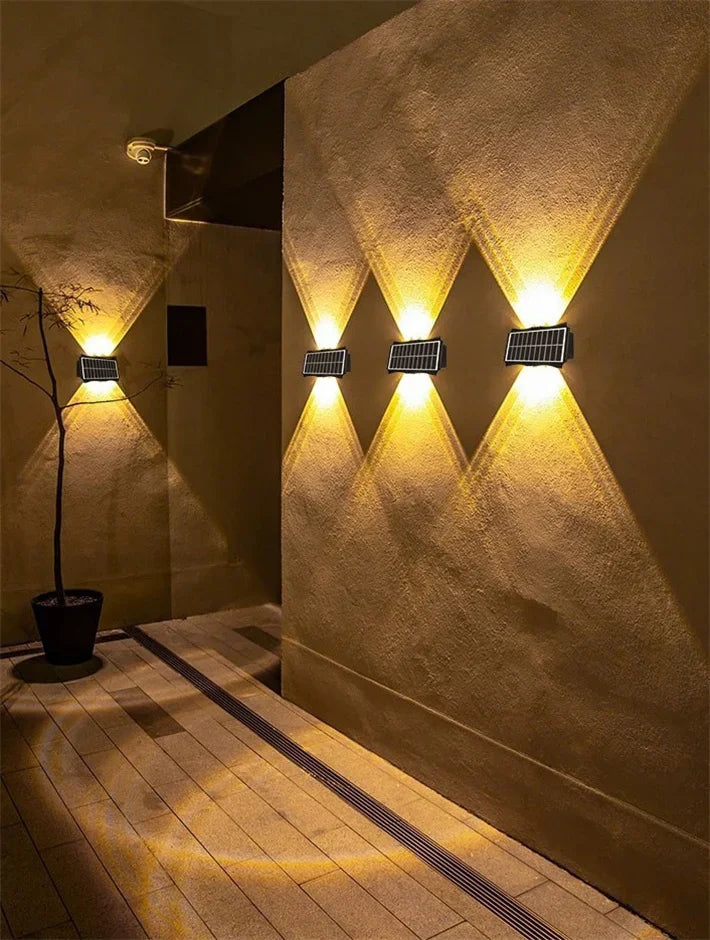 A wall featuring a pattern of upward-pointing LED lights illuminating a textured wall and a pathway.