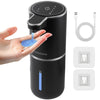 A black touchless automatic soap dispenser is shown dispensing blue liquid onto a hand, with charging cables and replacement 