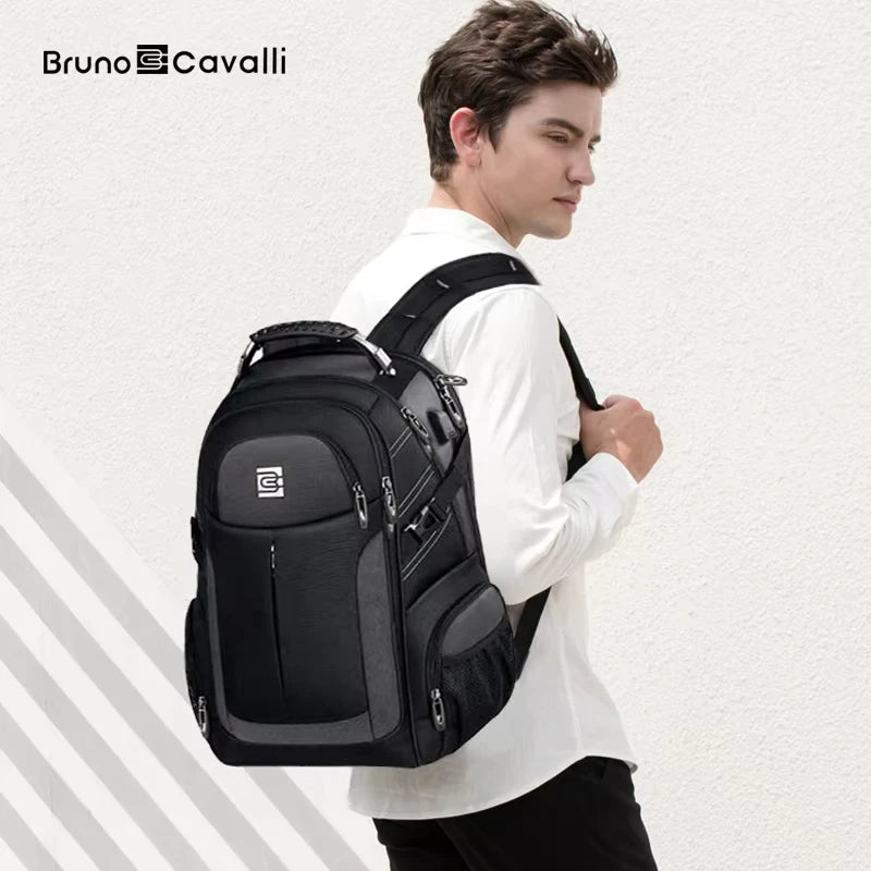 A man wearing a white shirt is holding a black large capacity waterproof laptop backpack.