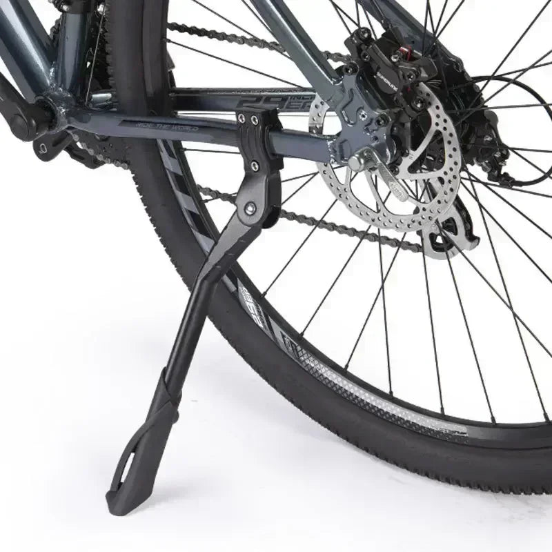 A close-up view of a black bicycle kickstand attached to the frame and wheel.