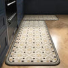 A long rectangular kitchen rug with a classic beige and black Persian print is placed on a light wood floor.