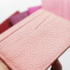 A close-up of a pink genuine leather slim card holder wallet with a quilted texture.