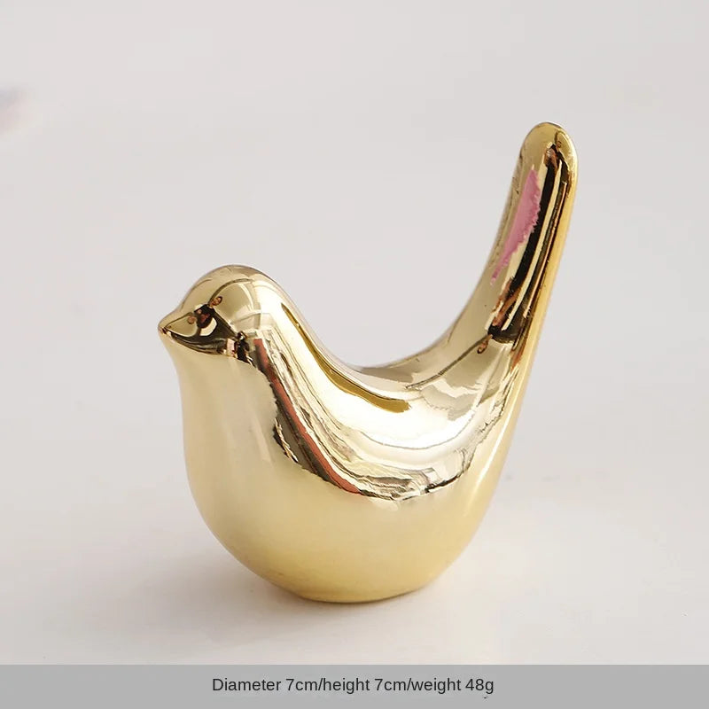 A small, golden ceramic elephant and rabbit jewelry holder with a smooth, curved design.