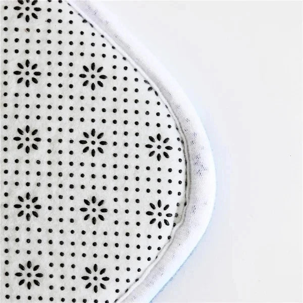Close-up of a black and white patterned non-slip door mat with a white border.