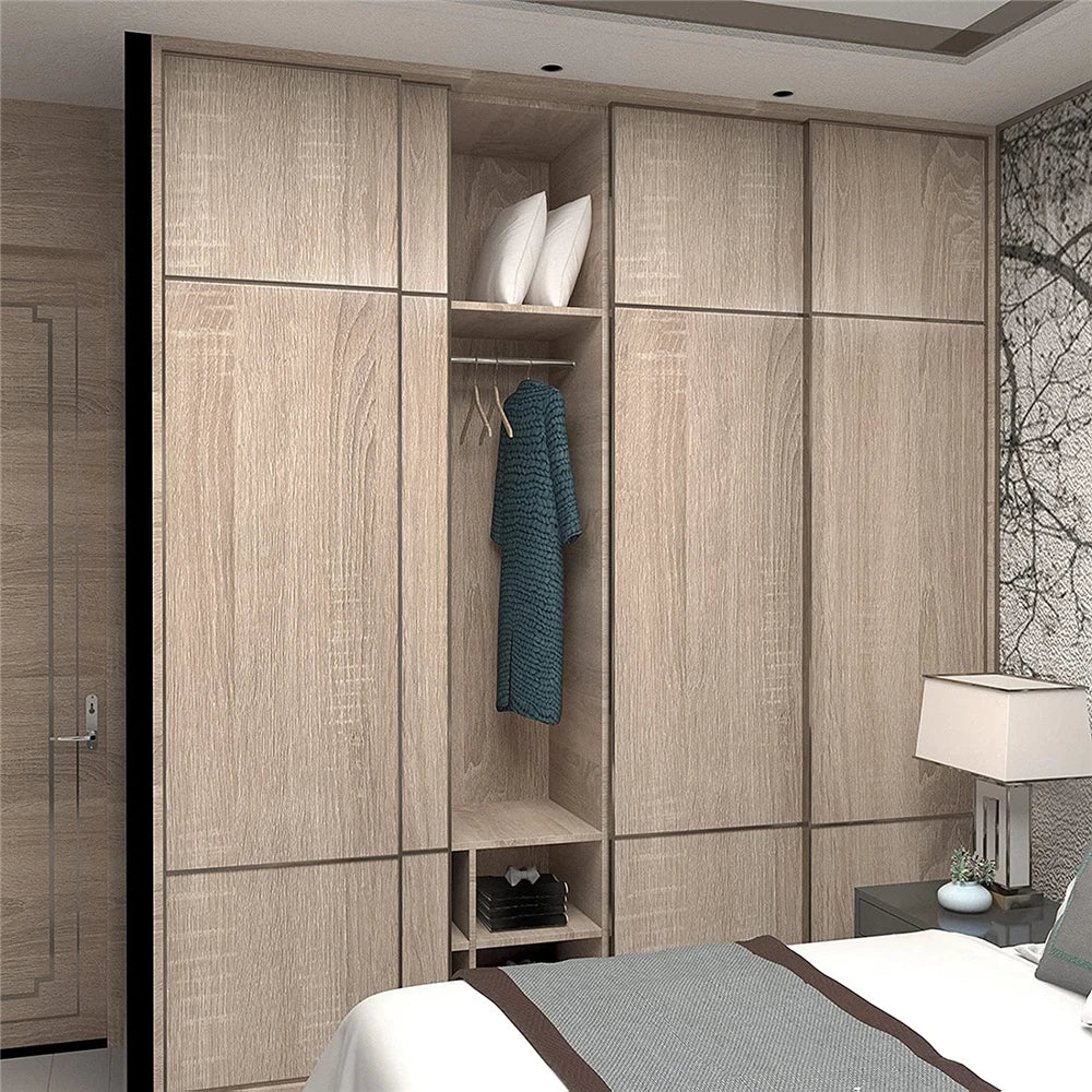 A modern bedroom closet featuring light wood grain vinyl wallpaper doors and shelving with white towels and a green garment.