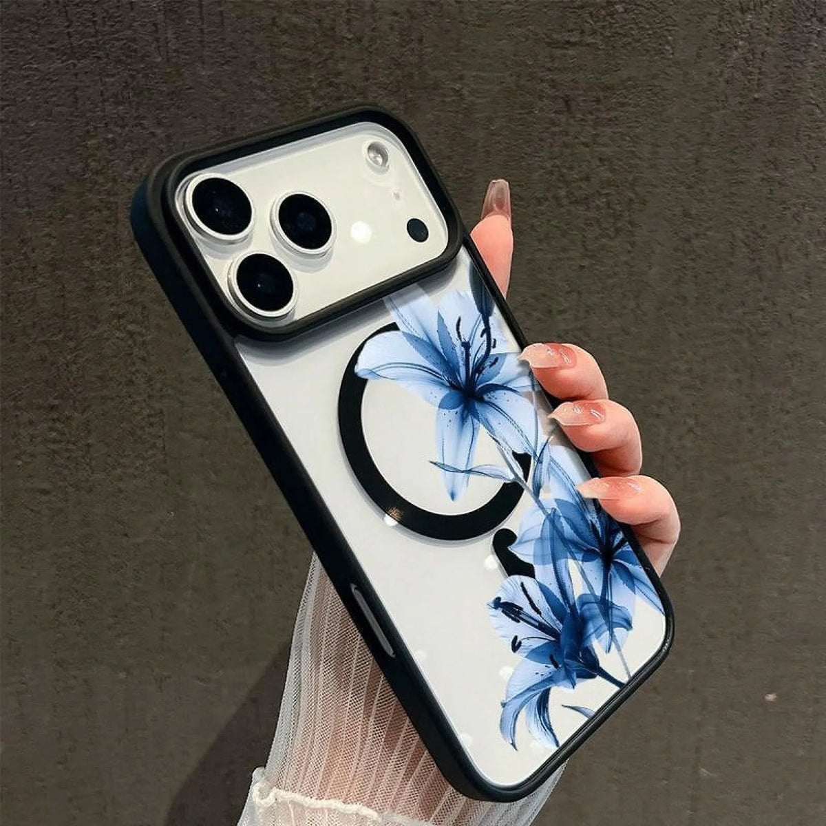 A hand holds a white phone case featuring blue lily floral artwork on the back.