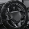 Close-up of a black winter plush steering wheel cover on a vehicle interior.