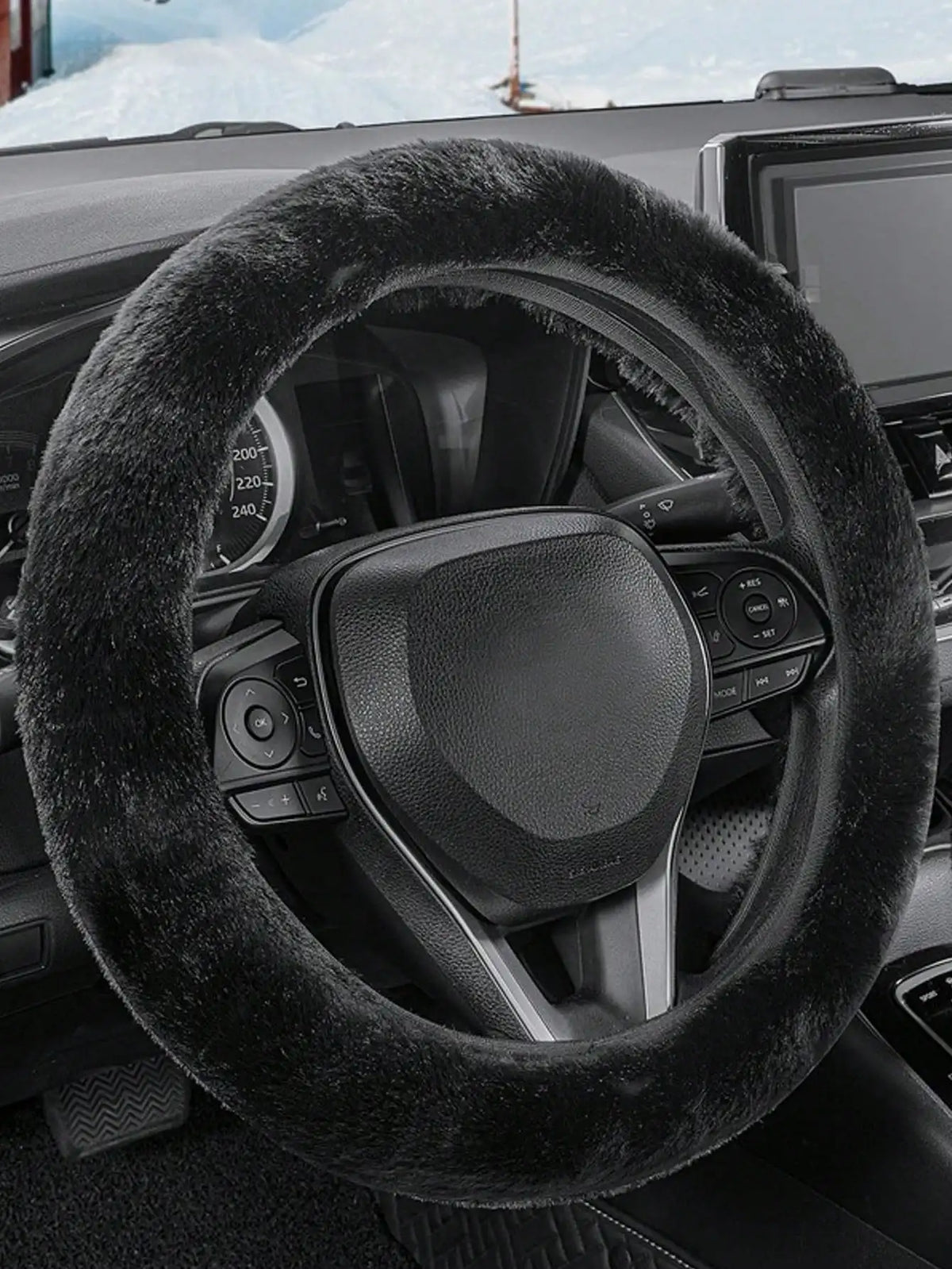 Close-up of a black winter plush steering wheel cover on a vehicle interior.