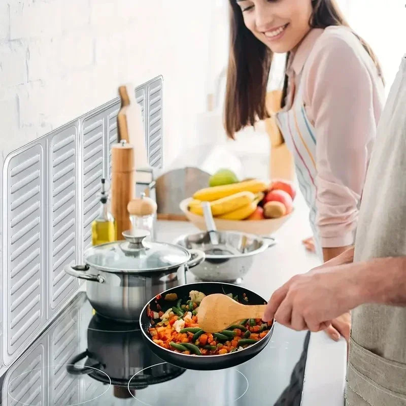 A person is cooking in a pan on a stovetop, with a foldable aluminum stove splatter guard visible.
