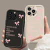 A pair of hands holds a black silicone phone case with a pink bow slogan and a beige iPhone case with a pink bow slogan.