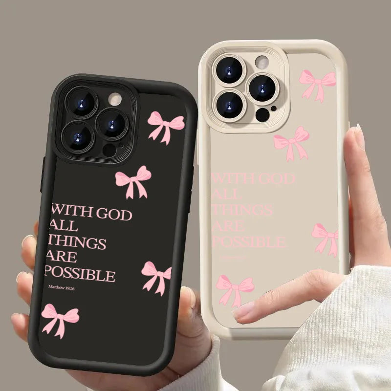A pair of hands holds a black silicone phone case with a pink bow slogan and a beige iPhone case with a pink bow slogan.