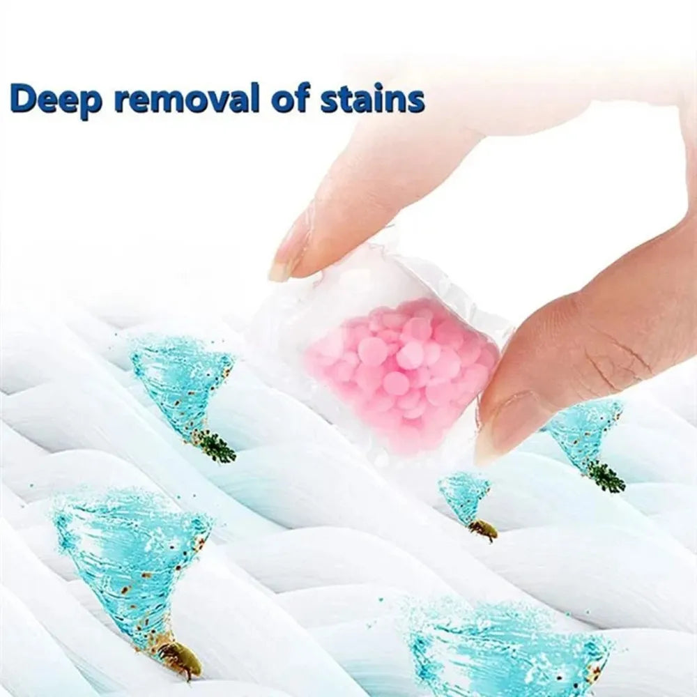 A hand is removing stains from white fabric using pink water-soluble laundry fragrance beads.