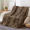 A brown and black leopard print flannel throw blanket draped over a light-colored sofa.