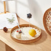 A handcrafted rattan serving tray holds a lemon and blueberries on a wooden table.