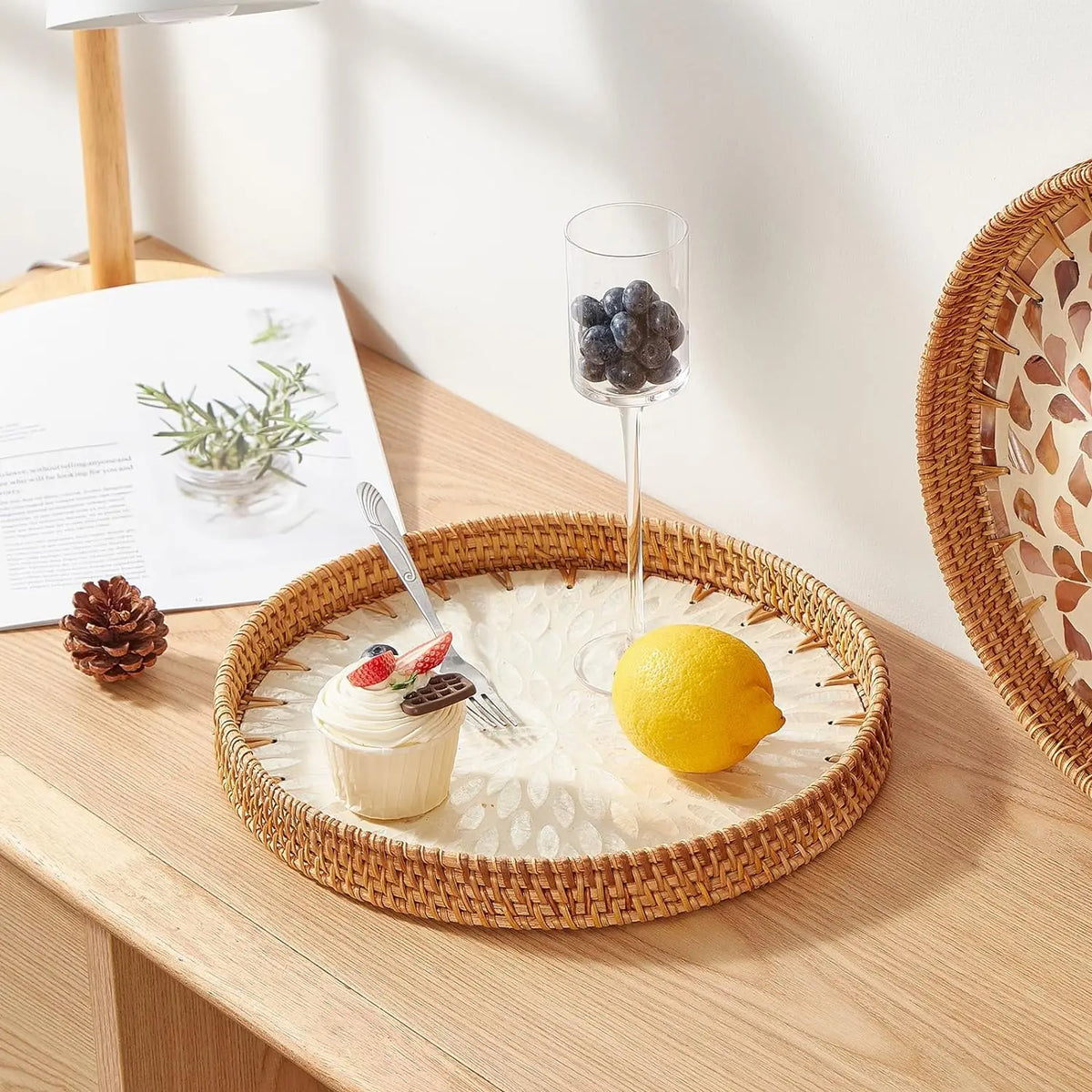 A handcrafted rattan serving tray holds a lemon and blueberries on a wooden table.