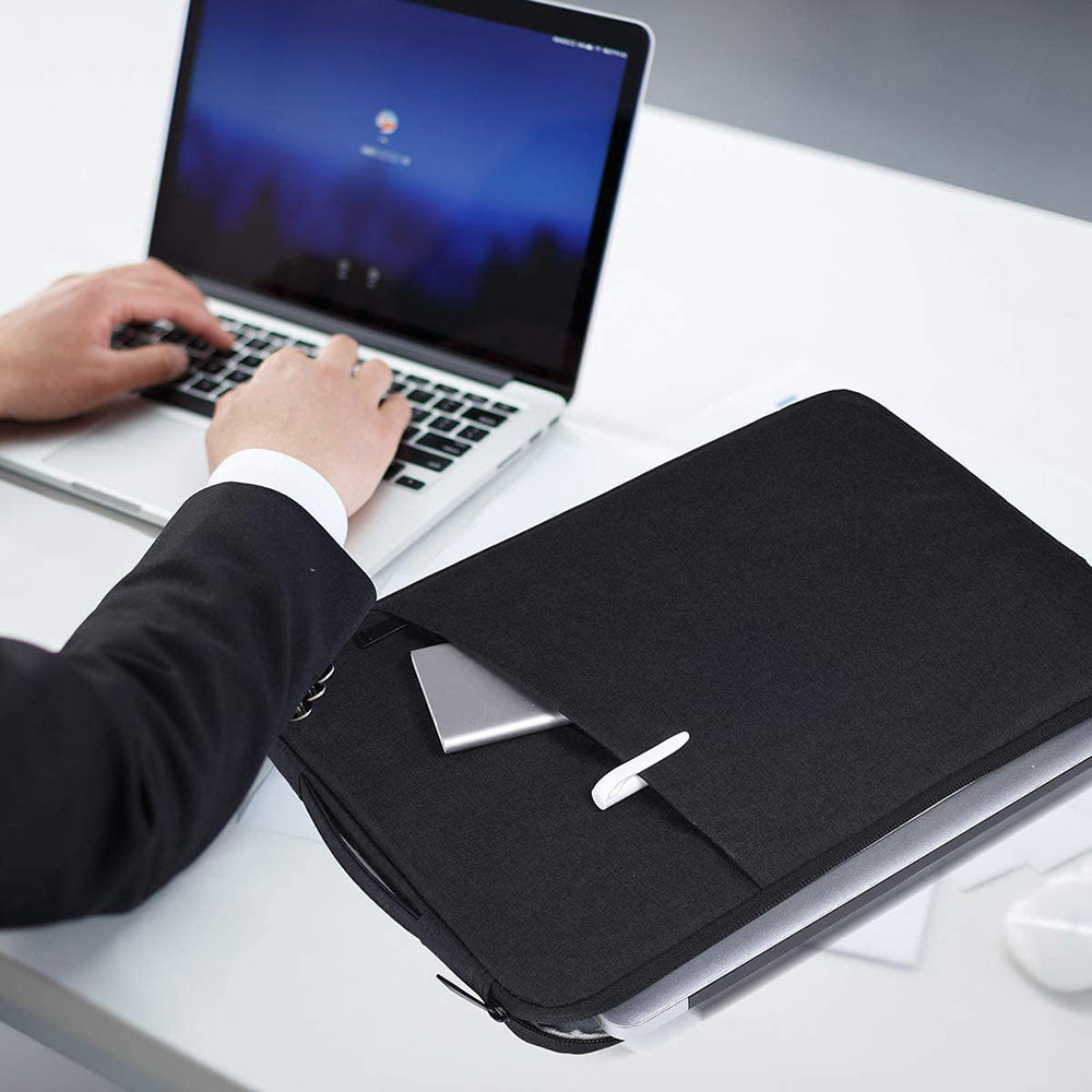 A person is using a laptop and a black waterproof laptop sleeve with a handle on a white desk.