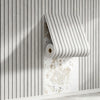 Roll of wood grain peel-and-stick wall tiles displayed against a vertical light gray wooden slat background.
