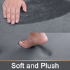 Close-up view of a gray plush memory foam bathroom mat showing a hand and foot pressing into the soft surface.