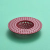A round, pink silicone sink drain filter strainer with a grid pattern.