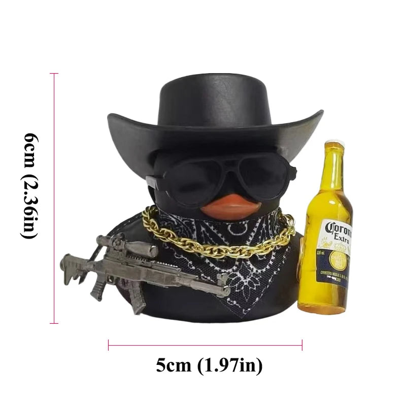A black cowboy rubber duck car ornament with a face, sunglasses, and a gold chain, next to a yellow bottle.