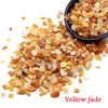 Yellow Jade natural tumbled crystal stone chips scattered on a white background.