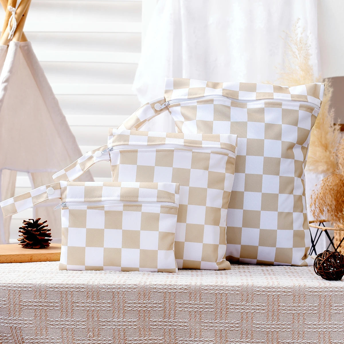 A set of four beige and white checkered reusable waterproof wet bags displayed on a table.