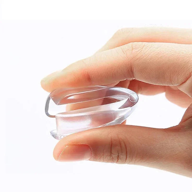 A hand holds a clear silicone corner edge guard designed for baby safety.