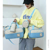 A woman wearing a yellow hoodie holds a light blue multifunctional crossbody diaper bag set.