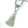 A set of two elegant sage green tassel curtain tiebacks tied together with a knot.