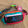 A colorful unisex water-resistant crossbody chest bag with orange, pink, and black panels resting on a tan fabric surface.