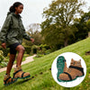 A person wearing adjustable lawn aerator shoes with heavy-duty spikes walking on a grassy slope.