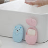 A pink and blue portable paper soap dispenser with a lid, resting on a white surface.