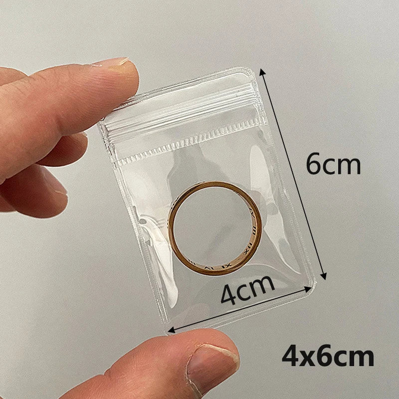 A hand holds a transparent jewelry pouch with a zip lock closure, measuring 6cm by 4cm.