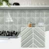 White herringbone marble peel-and-stick wall tiles installed on a kitchen backsplash.