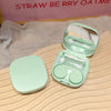 A light green compact contact lens travel case is shown open, displaying several clear lenses inside.