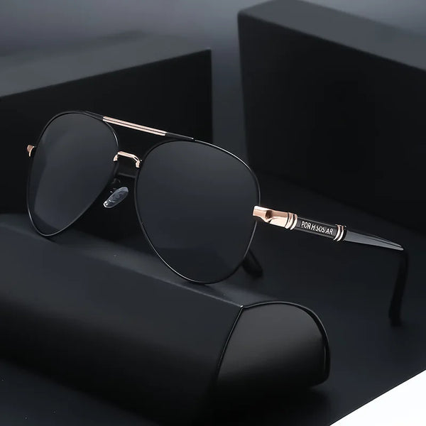 A pair of black polarized sunglasses with a gold-toned metal frame resting on a dark surface.