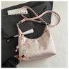 Hellrosa Satin-Crossbodytasche mit Perlenstickerei vor grauem Blazer und weißem Buch