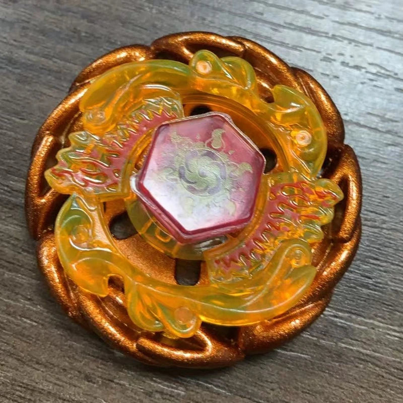 An orange alloy battle spinning top with a pink gemstone set in a gold-colored wooden frame.