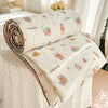 A rolled and unfolded cream-colored quilt featuring a pastoral print design with cute animal characters.