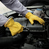 A person wearing yellow leather gardening gloves is working on the engine compartment of a vehicle.