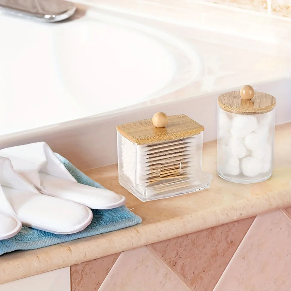 A set of cotton swabs and a glass organizer with a wooden lid placed on a bathroom counter.