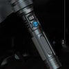 A close-up view of a black laser cannon flashlight with a digital LCD display and textured grip.