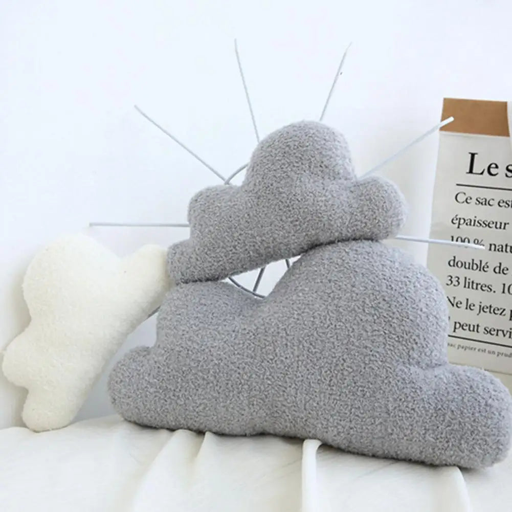 A stack of gray and white cloud-shaped plush pillows next to a brown informational card.