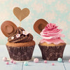 A cupcake decorated with chocolate frosting and topped by a miniature cowboy hat silhouette.